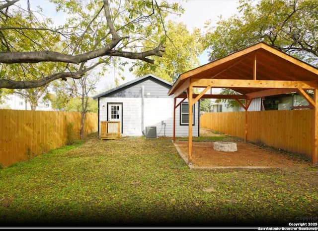 exterior space featuring a carport, a fenced backyard, a yard, and central AC