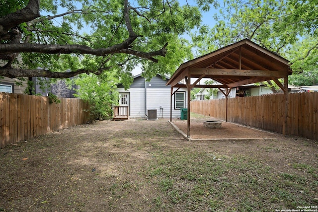 view of yard featuring a gazebo, central AC, a fenced backyard, and an outdoor fire pit
