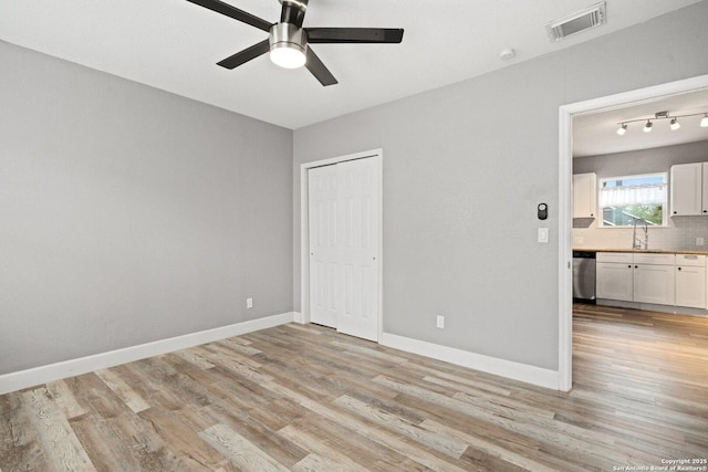 unfurnished bedroom with visible vents, a sink, light wood-type flooring, a closet, and baseboards