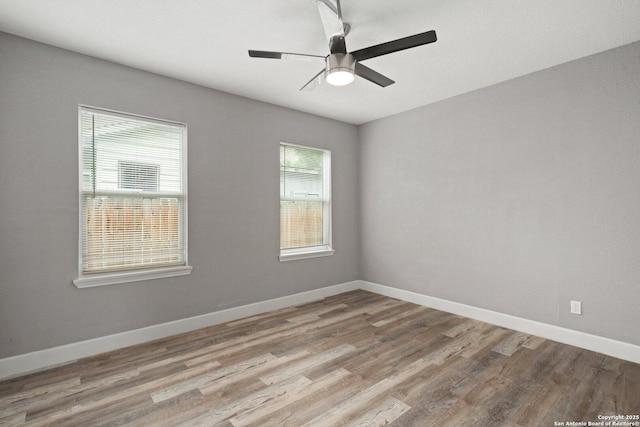 empty room with wood finished floors, a ceiling fan, and baseboards