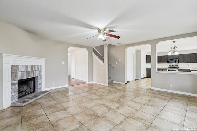 unfurnished living room featuring a brick fireplace, light tile patterned floors, and ceiling fan