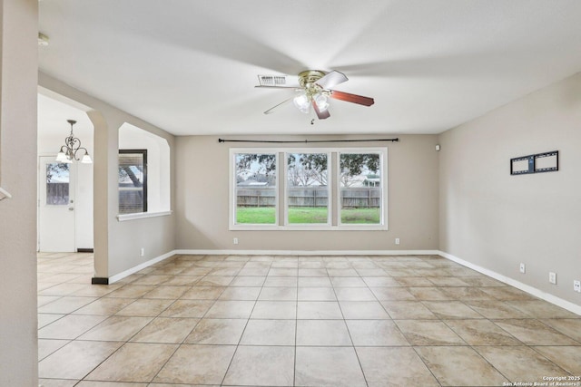 tiled spare room featuring ceiling fan with notable chandelier