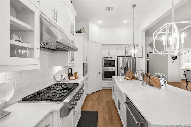 kitchen with sink, an inviting chandelier, decorative light fixtures, stainless steel appliances, and white cabinets