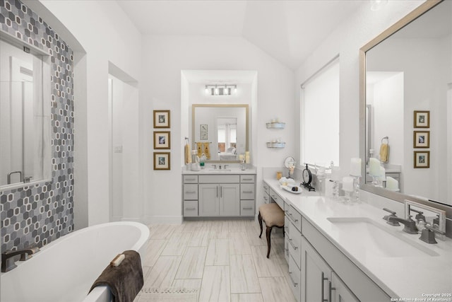 bathroom featuring vanity, vaulted ceiling, and independent shower and bath