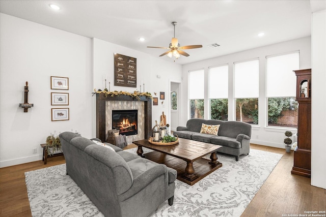 living room with hardwood / wood-style flooring, a premium fireplace, and ceiling fan