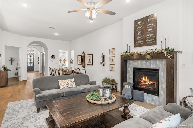 living room with a fireplace, light hardwood / wood-style flooring, and ceiling fan