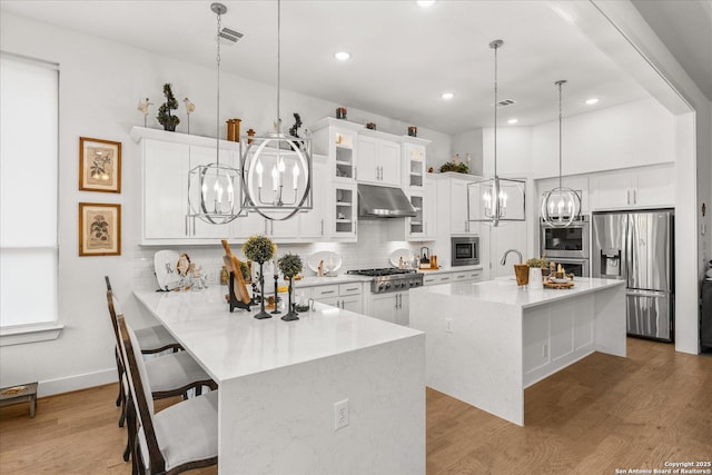 kitchen with a kitchen island with sink, a breakfast bar area, stainless steel appliances, and a chandelier