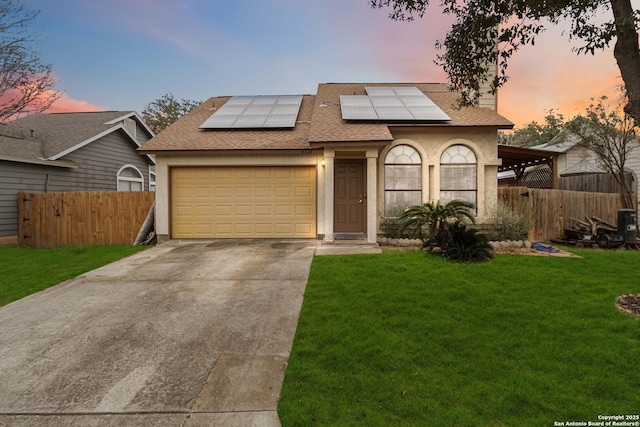 view of front of home with a garage, a lawn, and solar panels