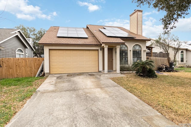 view of front of house featuring a garage, a front lawn, and solar panels