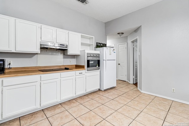 kitchen with light tile patterned flooring, stainless steel oven, white fridge, black electric stovetop, and white cabinets