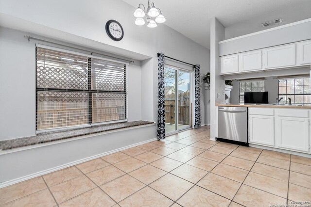 kitchen with stainless steel dishwasher, sink, light tile patterned floors, and white cabinets