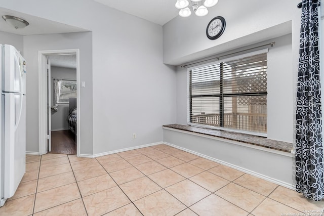 spare room with an inviting chandelier and light tile patterned floors