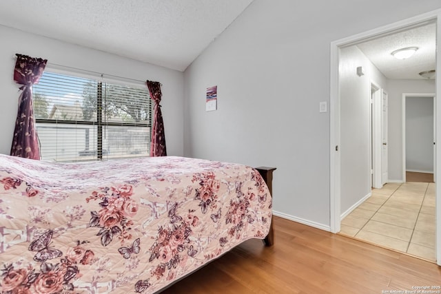 bedroom with wood-type flooring, a textured ceiling, and vaulted ceiling