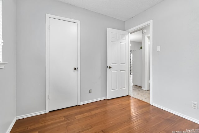 unfurnished bedroom with a textured ceiling and light wood-type flooring