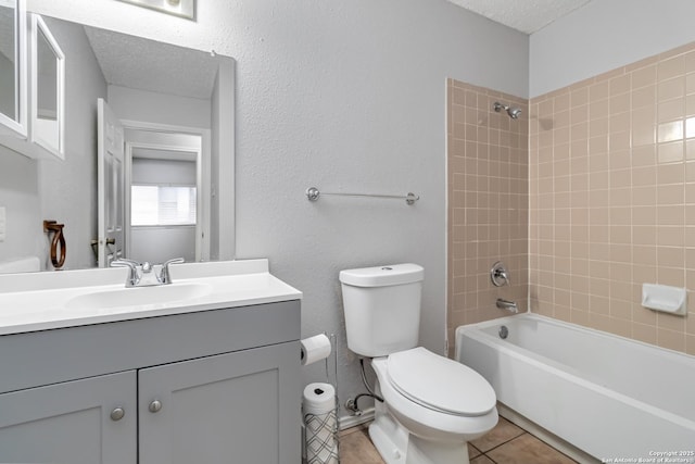 full bathroom featuring toilet, a textured ceiling, vanity, tiled shower / bath combo, and tile patterned flooring