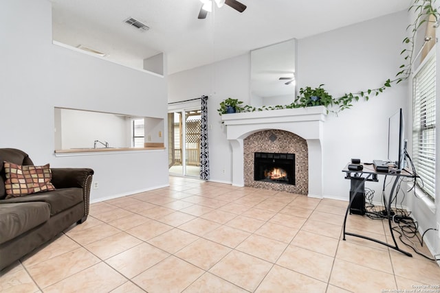 living room featuring ceiling fan, a tile fireplace, and light tile patterned floors