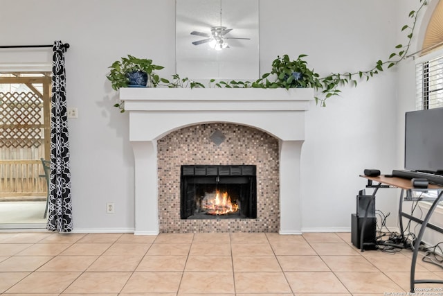 living room featuring a tiled fireplace, a towering ceiling, light tile patterned floors, and ceiling fan