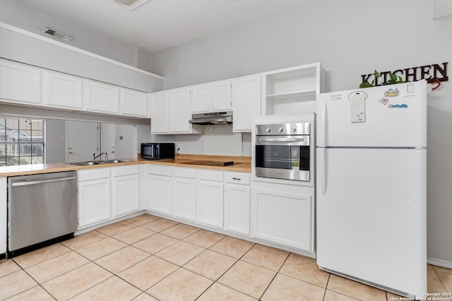 kitchen with light tile patterned floors, black appliances, sink, and white cabinets