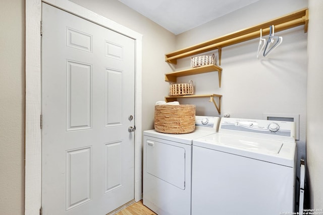 washroom with washing machine and clothes dryer and light hardwood / wood-style flooring