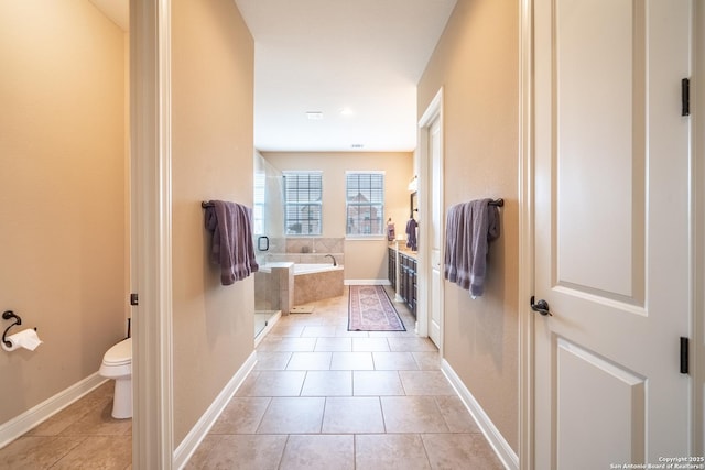 bathroom with toilet, tile patterned flooring, and tiled tub