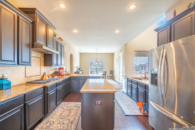 kitchen featuring sink, decorative light fixtures, a kitchen island, stainless steel appliances, and backsplash