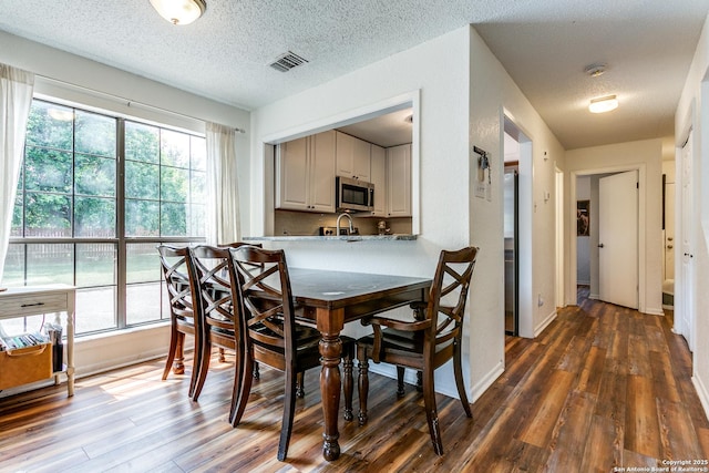 dining area with a textured ceiling and dark hardwood / wood-style flooring