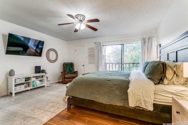 bedroom featuring ceiling fan, hardwood / wood-style floors, access to exterior, and a textured ceiling