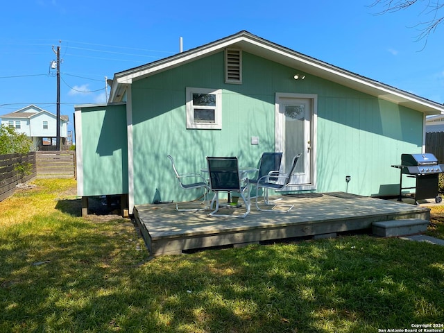 back of property featuring a wooden deck and a yard