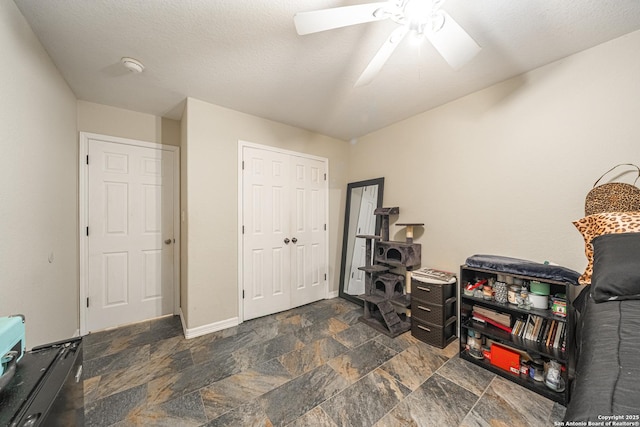 misc room featuring ceiling fan and a textured ceiling