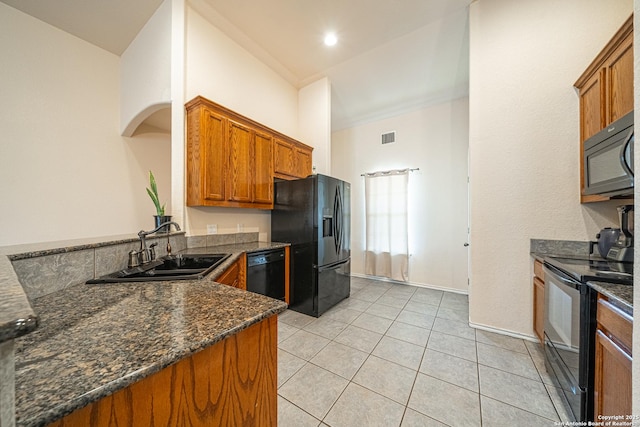 kitchen with sink, light tile patterned floors, dark stone countertops, kitchen peninsula, and black appliances