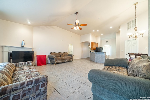 tiled living room featuring ceiling fan with notable chandelier and high vaulted ceiling