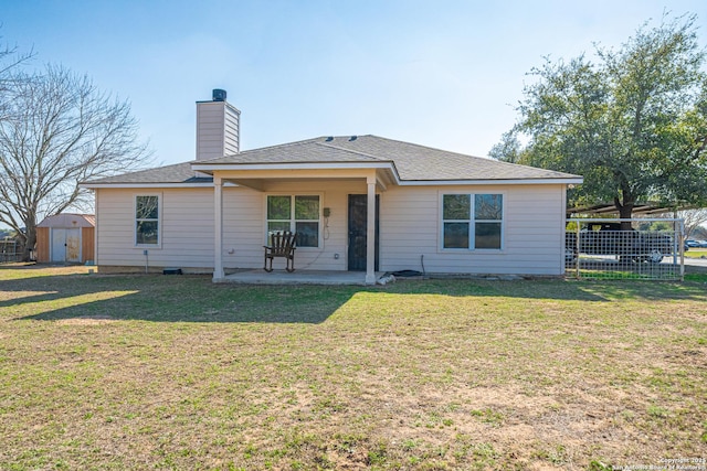 rear view of property with a yard, a patio, and a storage unit