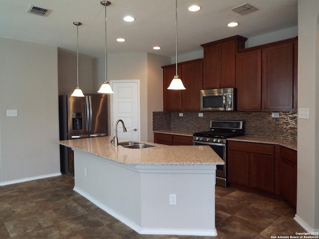 kitchen with pendant lighting, an island with sink, sink, backsplash, and stainless steel appliances