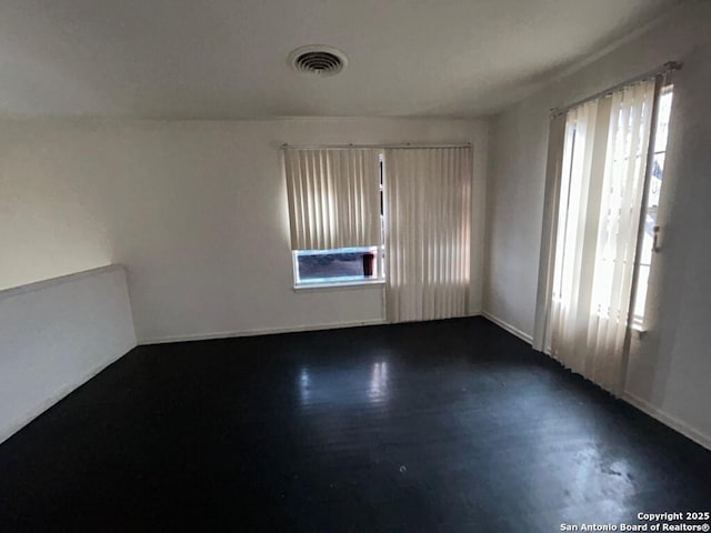 empty room featuring plenty of natural light and dark hardwood / wood-style flooring