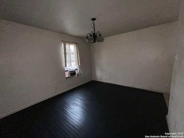 empty room with wood-type flooring, cooling unit, and a notable chandelier