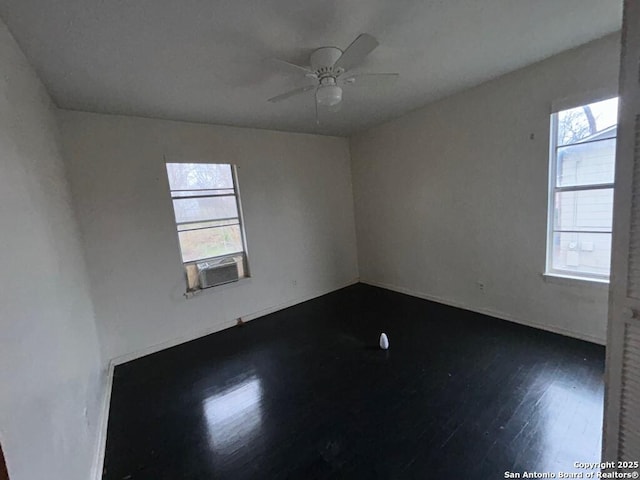 empty room featuring cooling unit, dark wood-type flooring, and ceiling fan