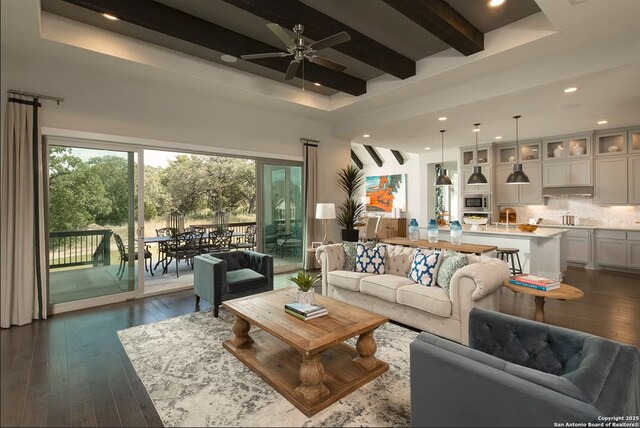 living room featuring dark hardwood / wood-style flooring, ceiling fan, and beamed ceiling