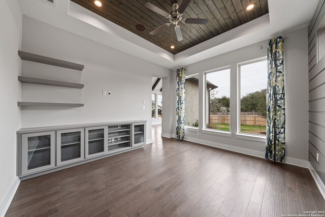 unfurnished living room with ceiling fan, dark hardwood / wood-style flooring, a raised ceiling, and wooden ceiling