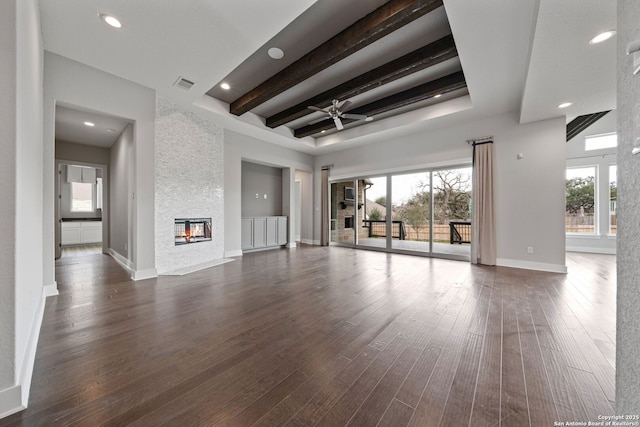 unfurnished living room with dark hardwood / wood-style floors, ceiling fan, a fireplace, and beam ceiling