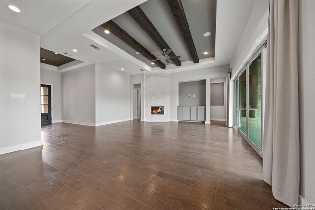 unfurnished living room with dark wood-type flooring, a large fireplace, and a wealth of natural light