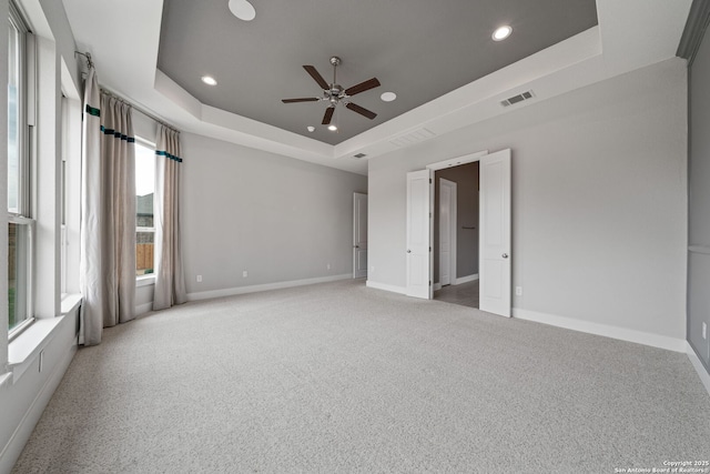 spare room with light colored carpet, a raised ceiling, and ceiling fan