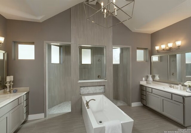 bathroom featuring an inviting chandelier, vanity, separate shower and tub, and vaulted ceiling