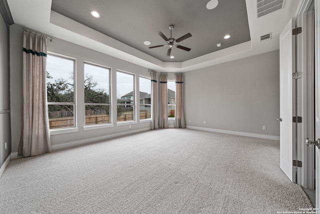 carpeted spare room with a tray ceiling and ceiling fan