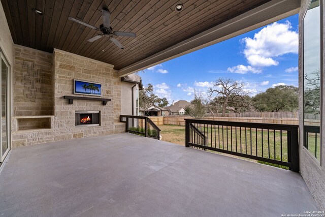 view of patio / terrace featuring ceiling fan and an outdoor stone fireplace