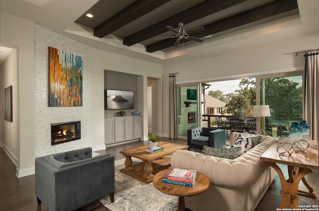 living room featuring beamed ceiling, ceiling fan, a large fireplace, and dark hardwood / wood-style floors