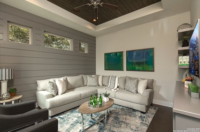 living room with wood walls, wood-type flooring, wooden ceiling, and a tray ceiling