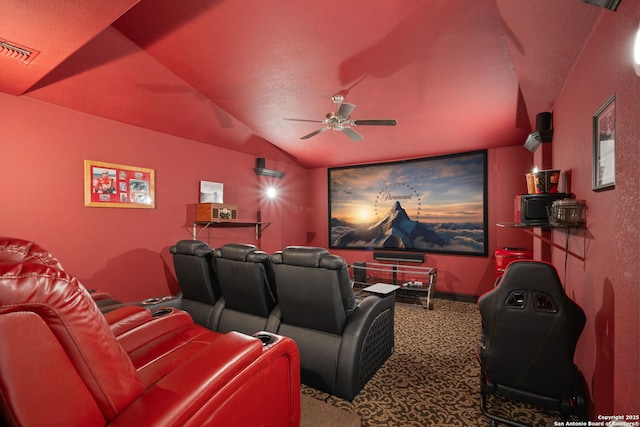 cinema room with a ceiling fan, carpet, visible vents, and vaulted ceiling