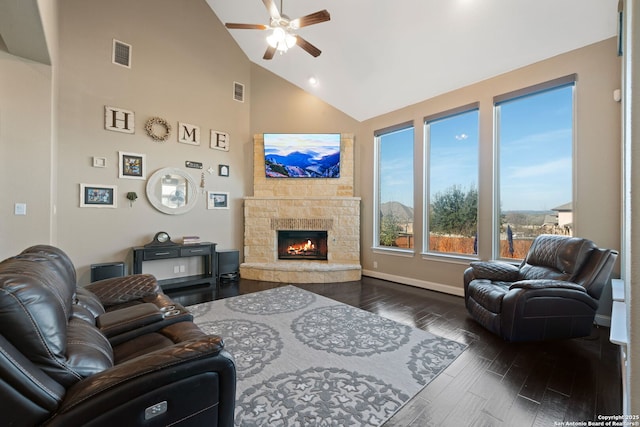 living room featuring high vaulted ceiling, visible vents, dark wood-type flooring, and a stone fireplace