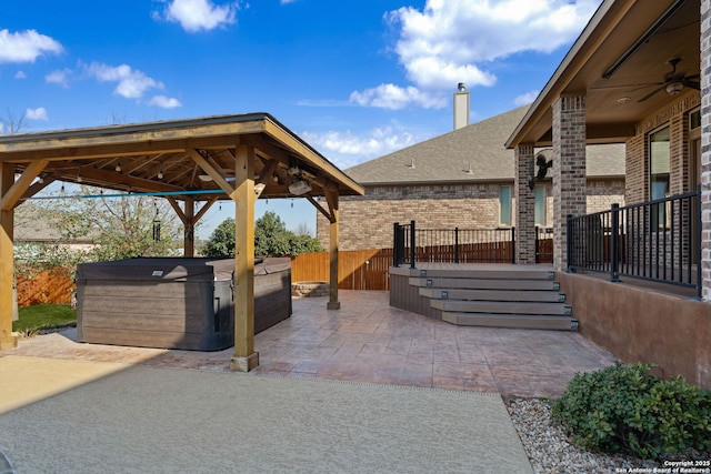 view of patio with a hot tub, ceiling fan, a fenced backyard, and a gazebo