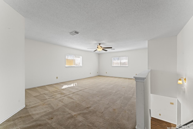 carpeted spare room featuring a textured ceiling and ceiling fan